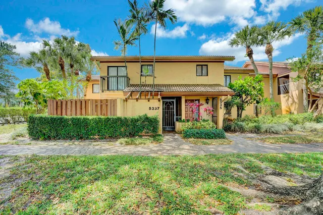 a front view of a house with a yard and potted plants