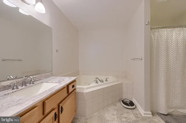a bathroom with a granite countertop sink and a bathtub