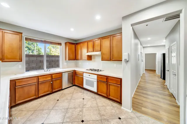 a large kitchen with stainless steel appliances granite countertop a large counter top a stove a sink dishwasher and a refrigerator