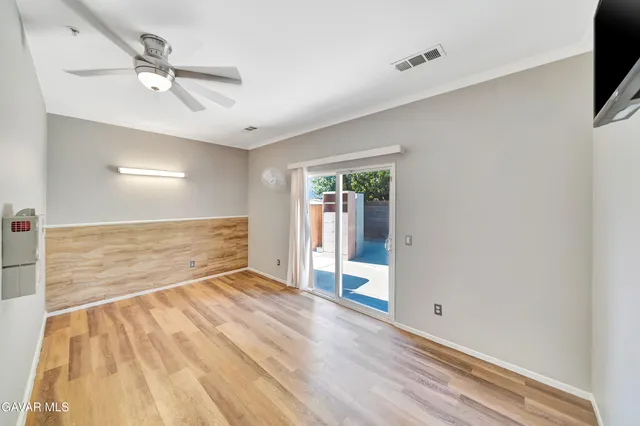 a view of empty room with wooden floor and fan