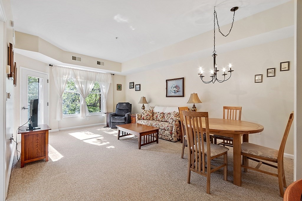 38 Village Road, Unit 310 Middleton, MA 01949 - Photo 4 of 18 a living room with furniture a window and a chandelier