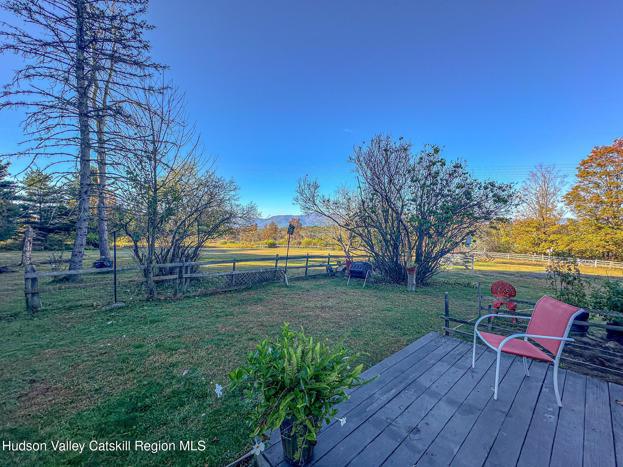 91 Drake Hill Road Greenville, NY 12431 - Photo 16 of 28 a view of a backyard with table and chairs under an umbrella with wooden fence