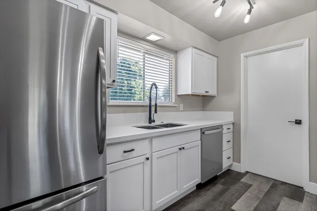 a kitchen with stainless steel appliances a sink cabinets and a window