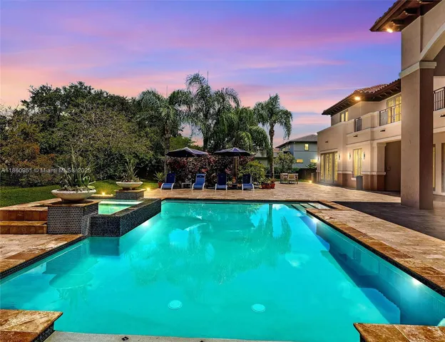 a view of swimming pool with a yard and palm trees