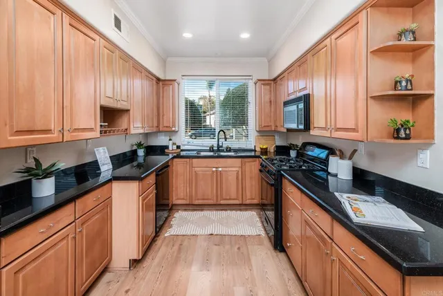a kitchen with granite countertop wooden cabinets stainless steel appliances a sink and a window