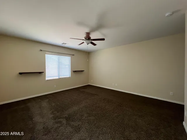 an empty room with a ceiling fan and wooden floor