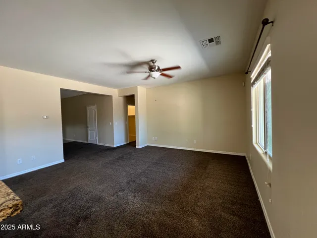 an empty room with a ceiling fan and windows