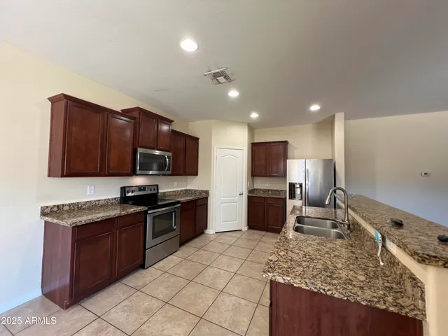 a kitchen with stainless steel appliances granite countertop a sink stove and refrigerator