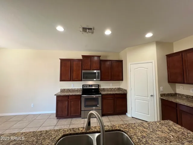 a kitchen with stainless steel appliances granite countertop a stove a sink dishwasher a refrigerator and a microwave