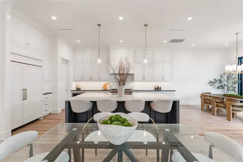 a large white kitchen with a stove a sink a window and a dining table