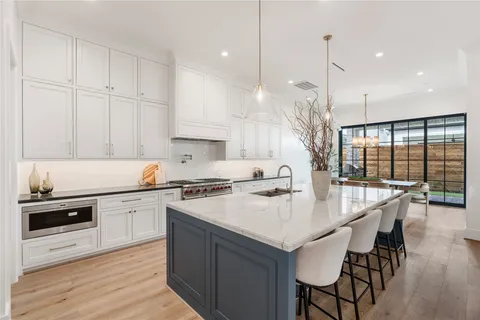 a spacious en suite bathroom with a granite countertop double vanity sink a mirror and a bathtub