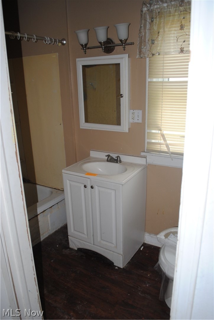 16110 Rockside Road Maple Heights, OH 44137 - Photo 14 of 17 Bathroom featuring a white vanity with integrated sink, wood-finish flooring, a wall-mounted medicine cabinet, and a three-light vanity fixture