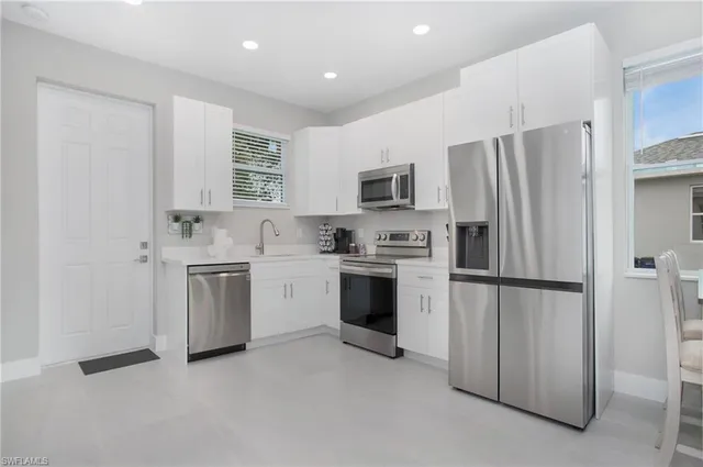a kitchen with white cabinets stainless steel appliances and a refrigerator