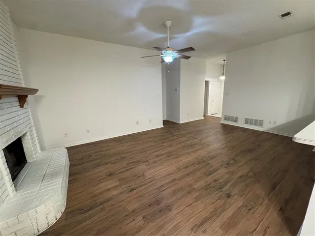 a view of an empty room with wooden floor and a fireplace