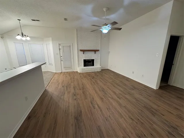 an empty room with wooden floor and stainless steel appliances
