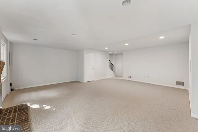 an empty room with windows and fireplace