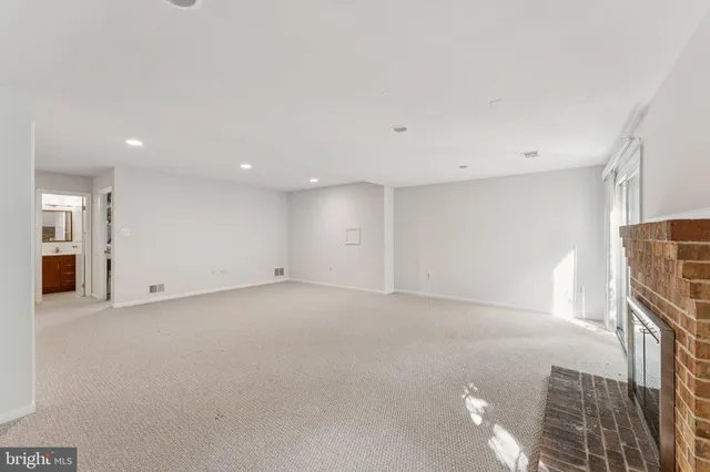an empty room with windows fireplace and wooden floor