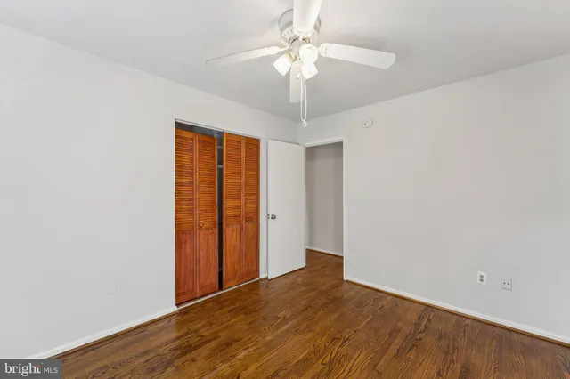 an empty room with wooden floor chandelier fan and windows