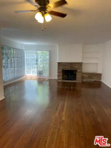 a view of an empty room with wooden floor fireplace and a window
