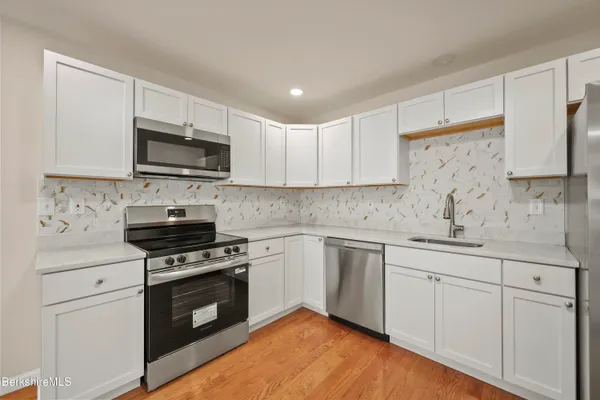 a kitchen with cabinets stainless steel appliances a sink and wooden floor