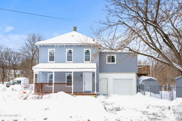 a front view of a house with a yard covered in snow