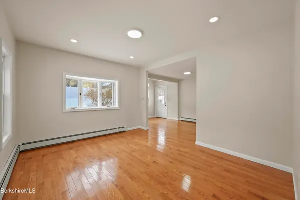 a view of empty room with wooden floor and fan