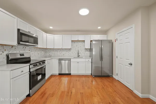 a kitchen with granite countertop a refrigerator and a stove top oven