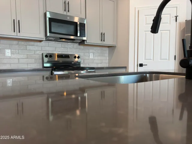 a kitchen with granite countertop a stove a sink a microwave and cabinets