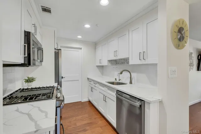 a kitchen with stainless steel appliances granite countertop a sink stove refrigerator and cabinets