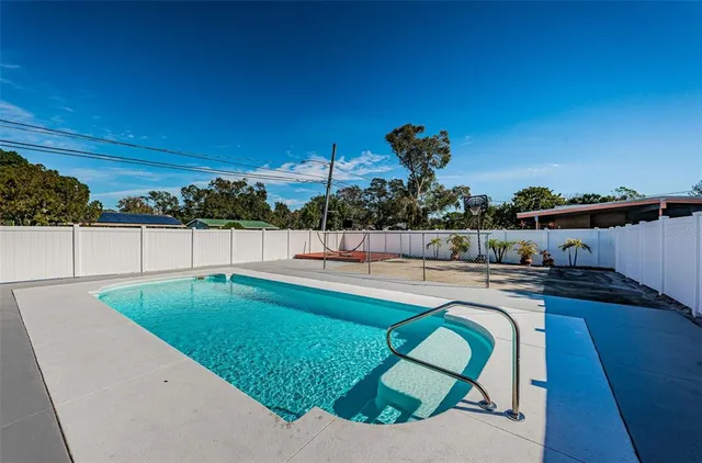 a backyard of a house with table and chairs under an umbrella
