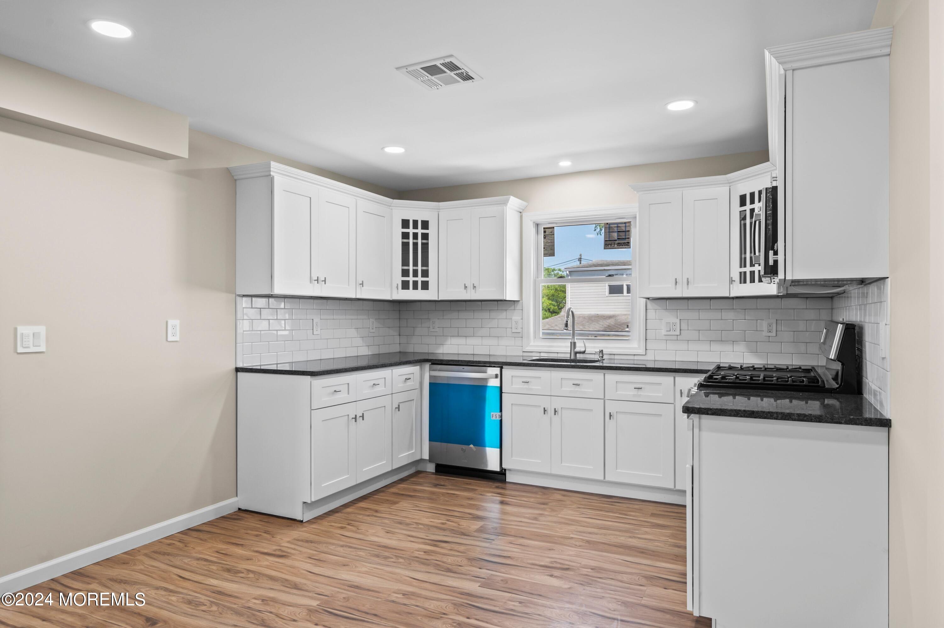 124 Victoria Place Union Beach, NJ 07735 - Photo 4 of 29 a kitchen with stainless steel appliances granite countertop a stove and white cabinets