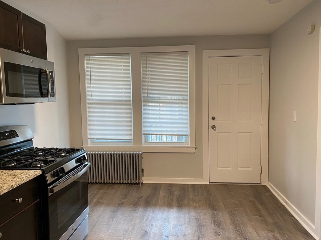 200 Congress Avenue, Unit 3 Chelsea, MA 02150 - Photo 3 of 14 a kitchen with granite countertop a stove and a wooden cabinets