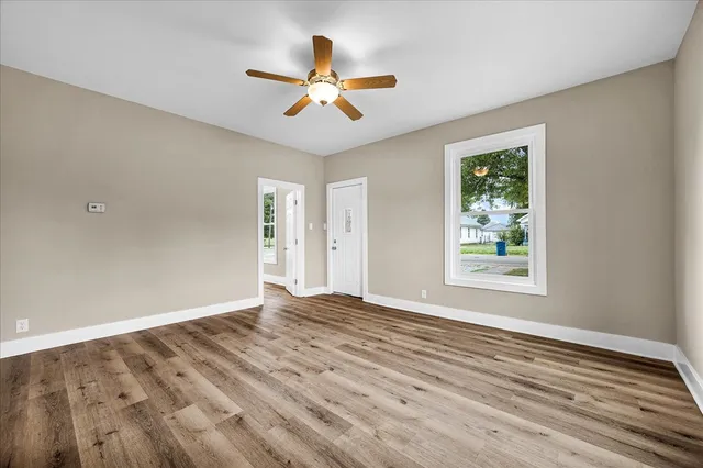 a view of an empty room with wooden floor and a window