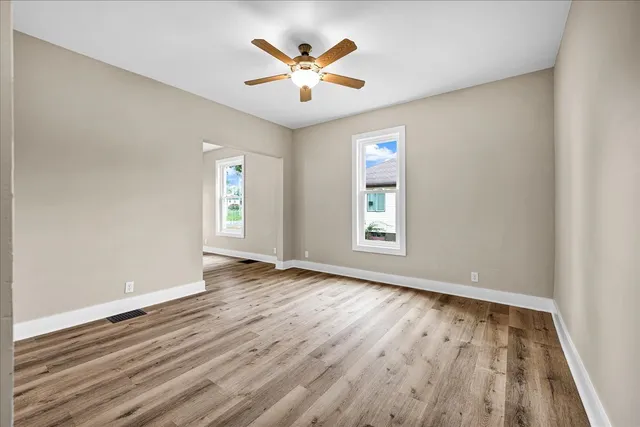 an empty room with wooden floor and windows