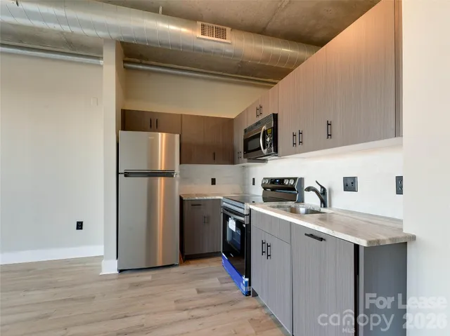 a kitchen with stainless steel appliances granite countertop a refrigerator a sink and a stove