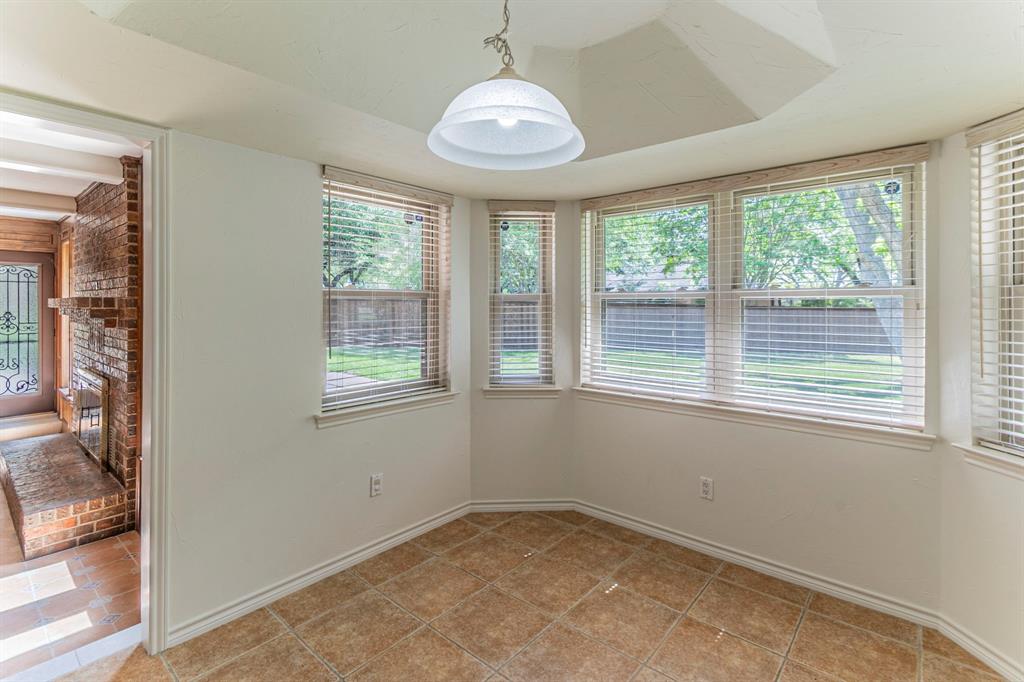 127 Nicklaus Nook Lancaster, TX 75146 - Photo 13 of 37 Unfurnished dining area with plenty of natural light, brick wall, a fireplace, and light tile patterned floors