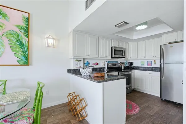 a kitchen with granite countertop a refrigerator stove top oven and sink
