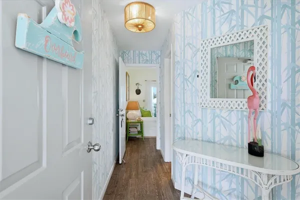 a view of a hallway to a livingroom with wooden floor and a bathroom view