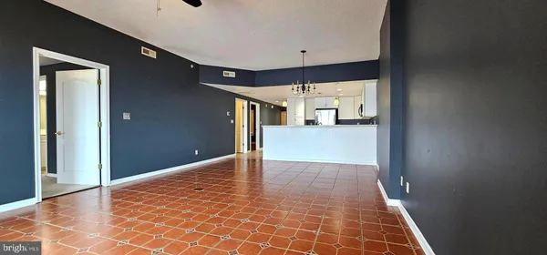 a view of a hallway to an empty room with a kitchen