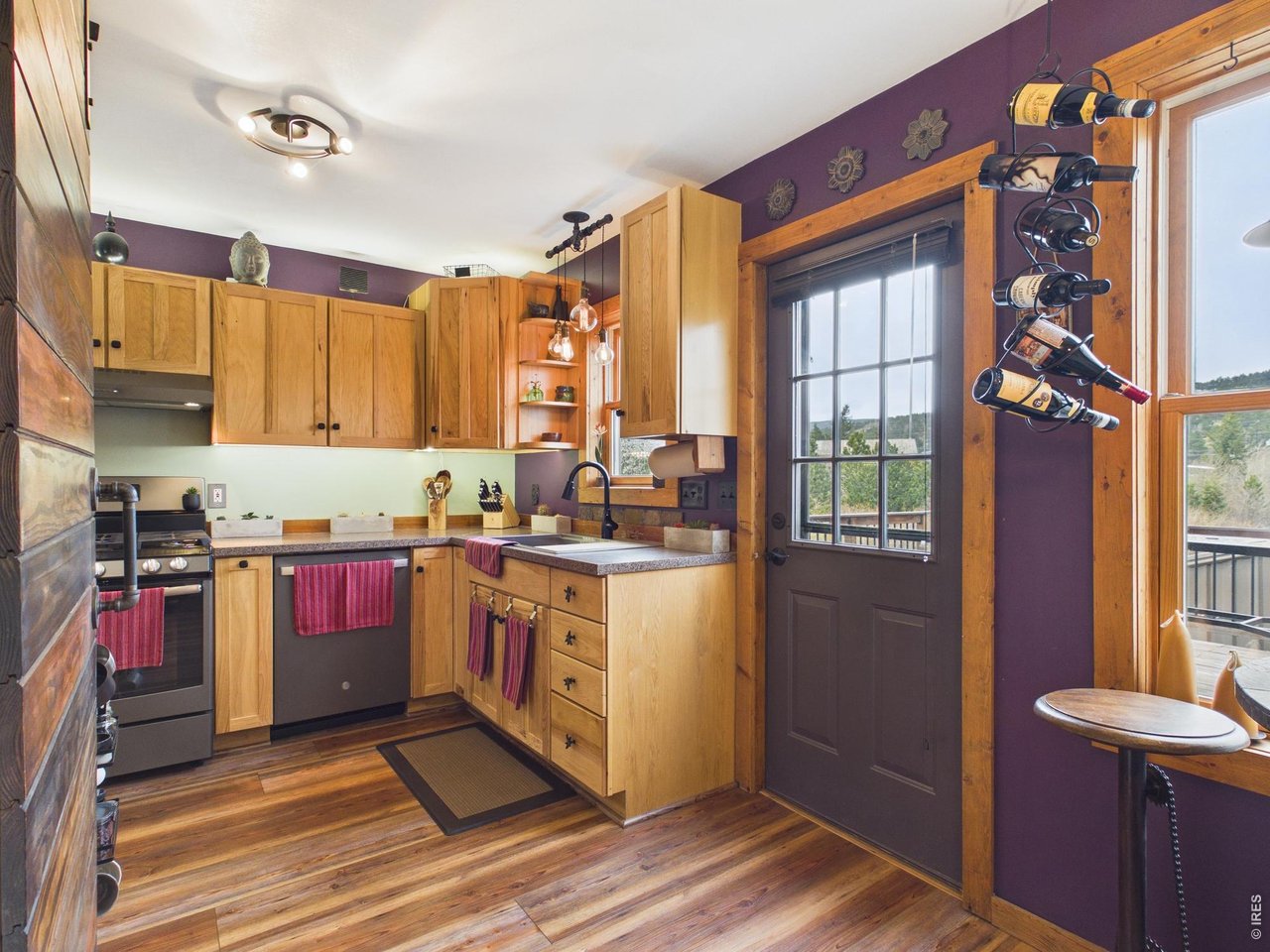 131 West Boulder Street Nederland, CO 80466 - Photo 8 of 46 Custom cabinetry, lots of windows with light, hanging wine rack, bistro table and chairs, open kitchen.