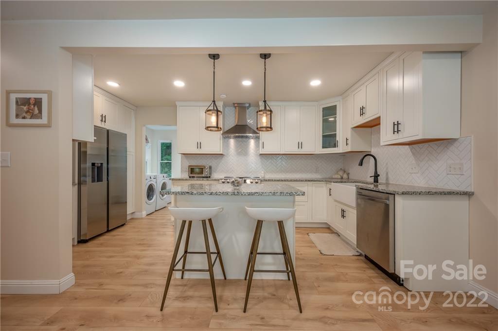 111 Jervey Road Tryon, NC 28782 - Photo 2 of 34 a kitchen with stainless steel appliances kitchen island granite countertop a stove a sink a refrigerator and white cabinets with wooden floor