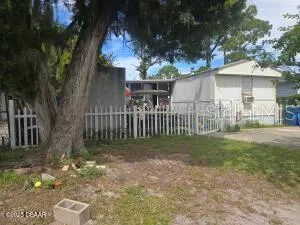a view of a house with a small yard and a large tree