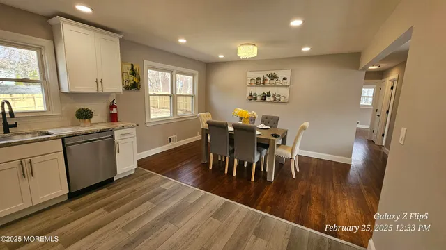 a kitchen with stainless steel appliances kitchen island granite countertop a refrigerator oven a sink a dining table and chairs with wooden floor
