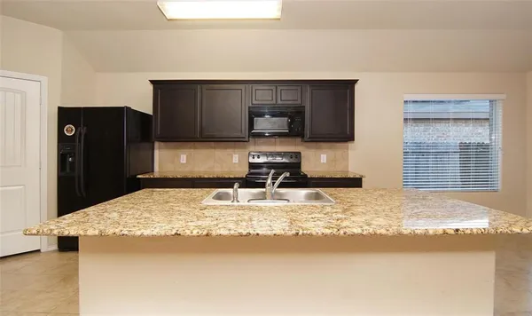 a kitchen with kitchen island granite countertop a refrigerator and a sink