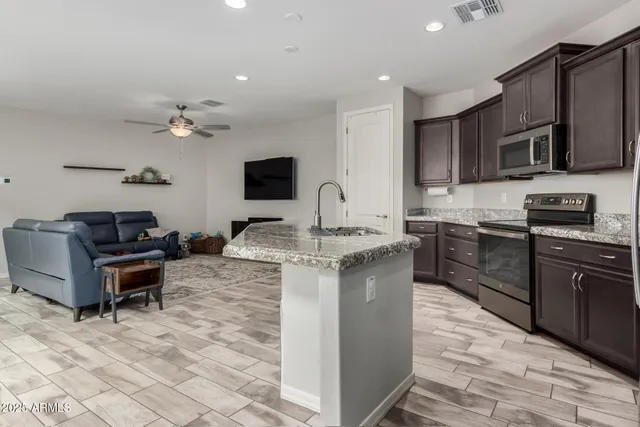 a kitchen with stainless steel appliances granite countertop a stove top oven a sink dishwasher a dining table and chairs with wooden floor