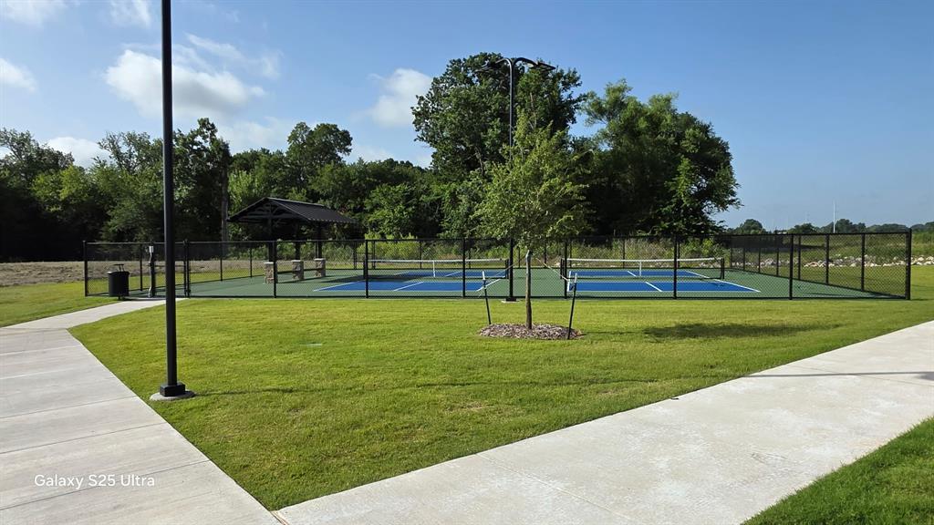 1614 Potomac Lane Blue Ridge, TX 75424 - Photo 14 of 18 Outdoor recreation area featuring two blue pickleball courts, a black chain-link fence perimeter, and a shaded picnic pavilion