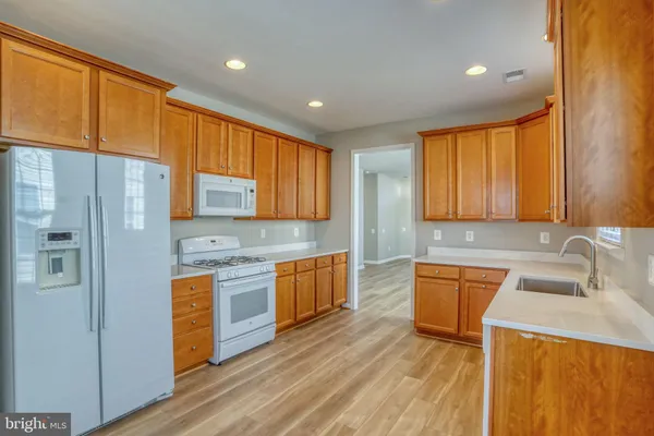 a kitchen with stainless steel appliances granite countertop wooden cabinets a sink and dishwasher with wooden floor
