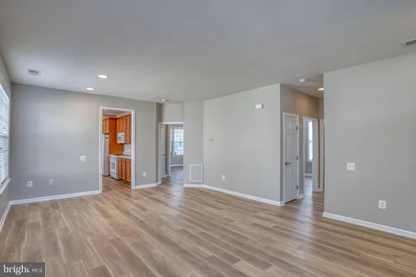 a view of an empty room with wooden floor and closet