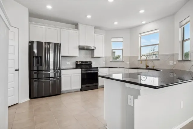 a kitchen with granite countertop white cabinets white appliances a sink and a large window