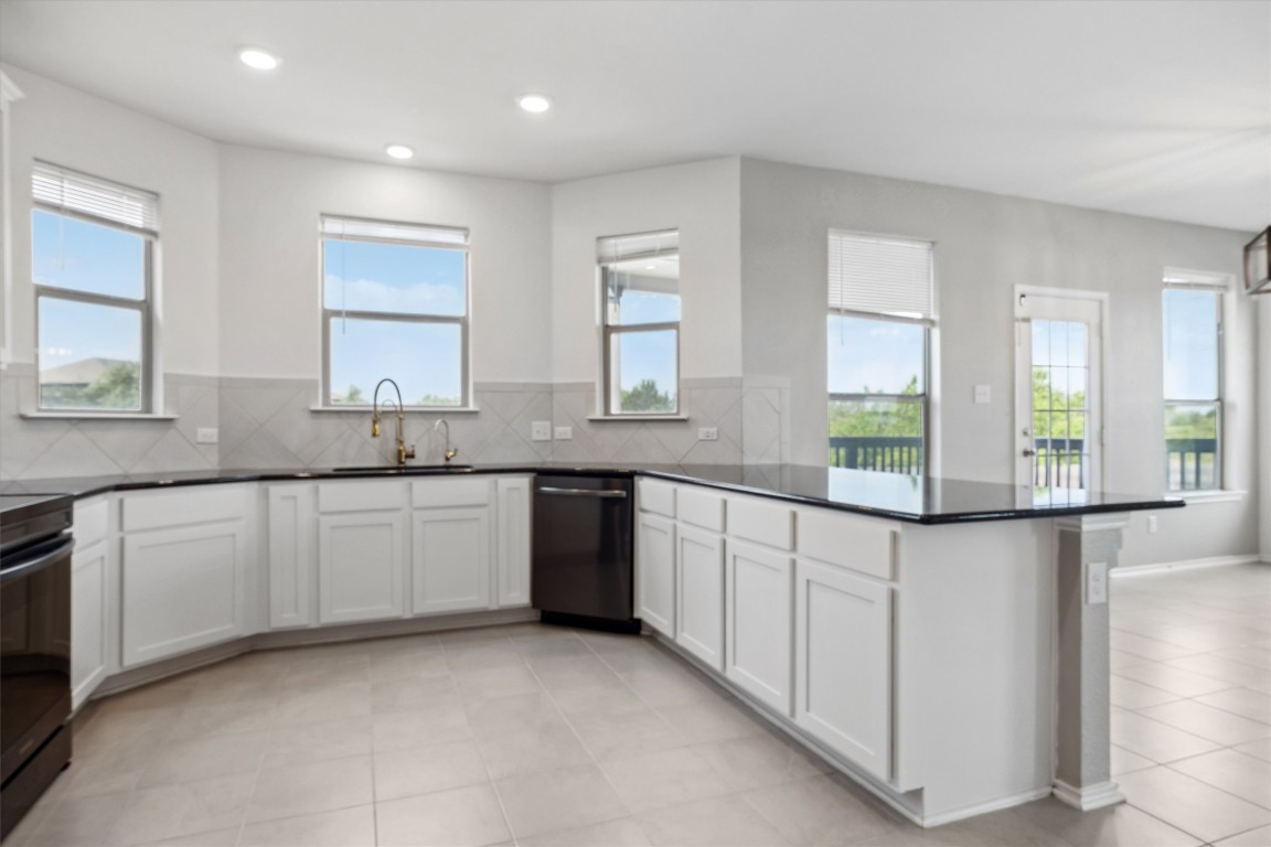 925 Yellow Ribbon Trail Jarrell, TX 76537 - Photo 10 of 35 a kitchen with granite countertop white cabinets white appliances a sink and a large window